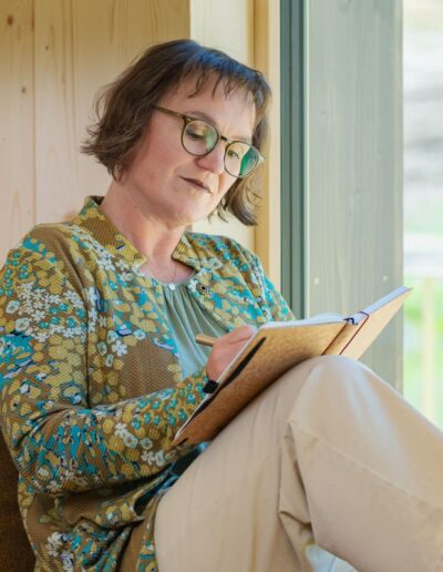 Die Wandlerin sitzt am Fenster und schreibt in ein Notizbuch